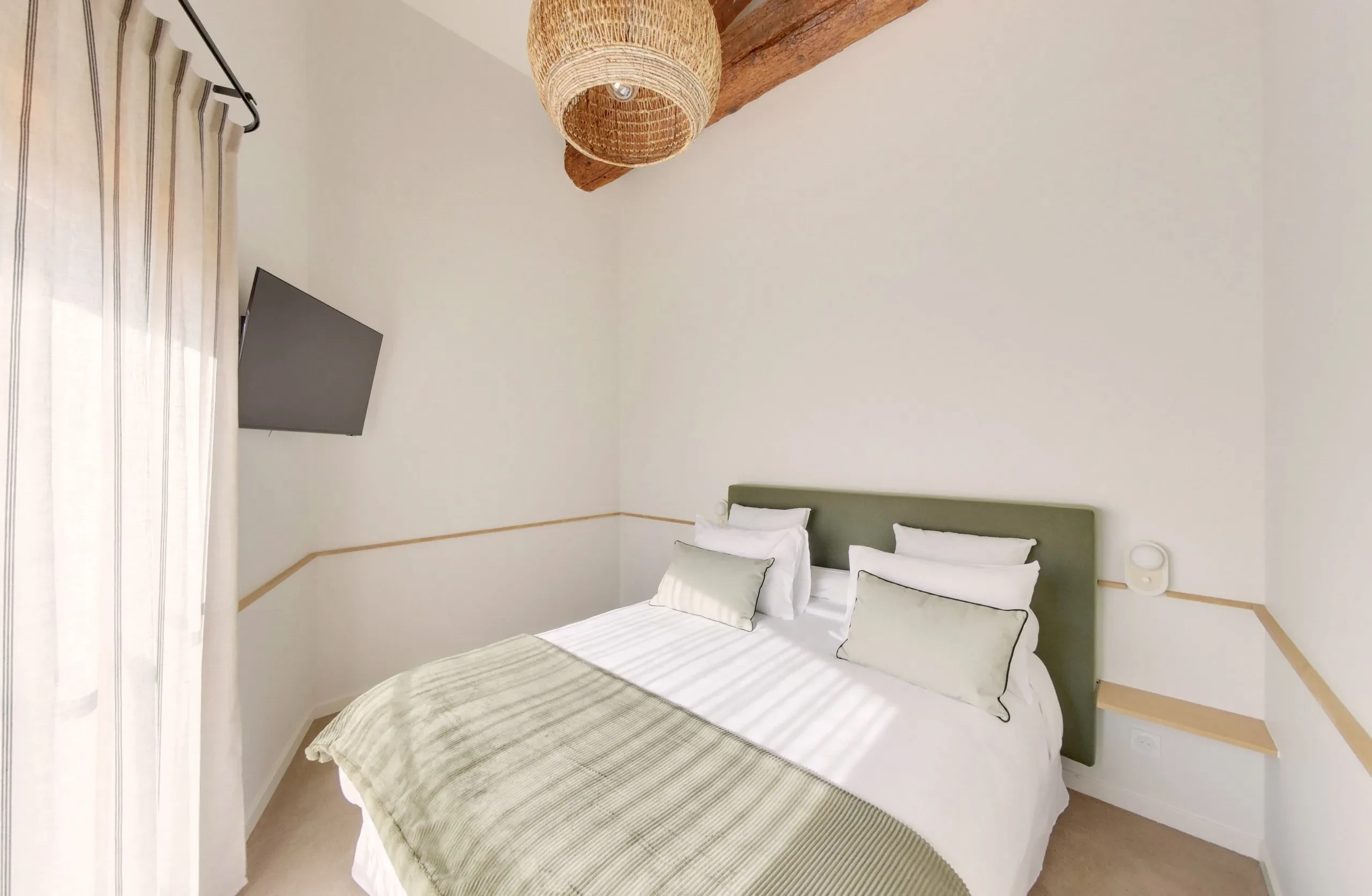 Chambre minimaliste avec lit double et télévision.
