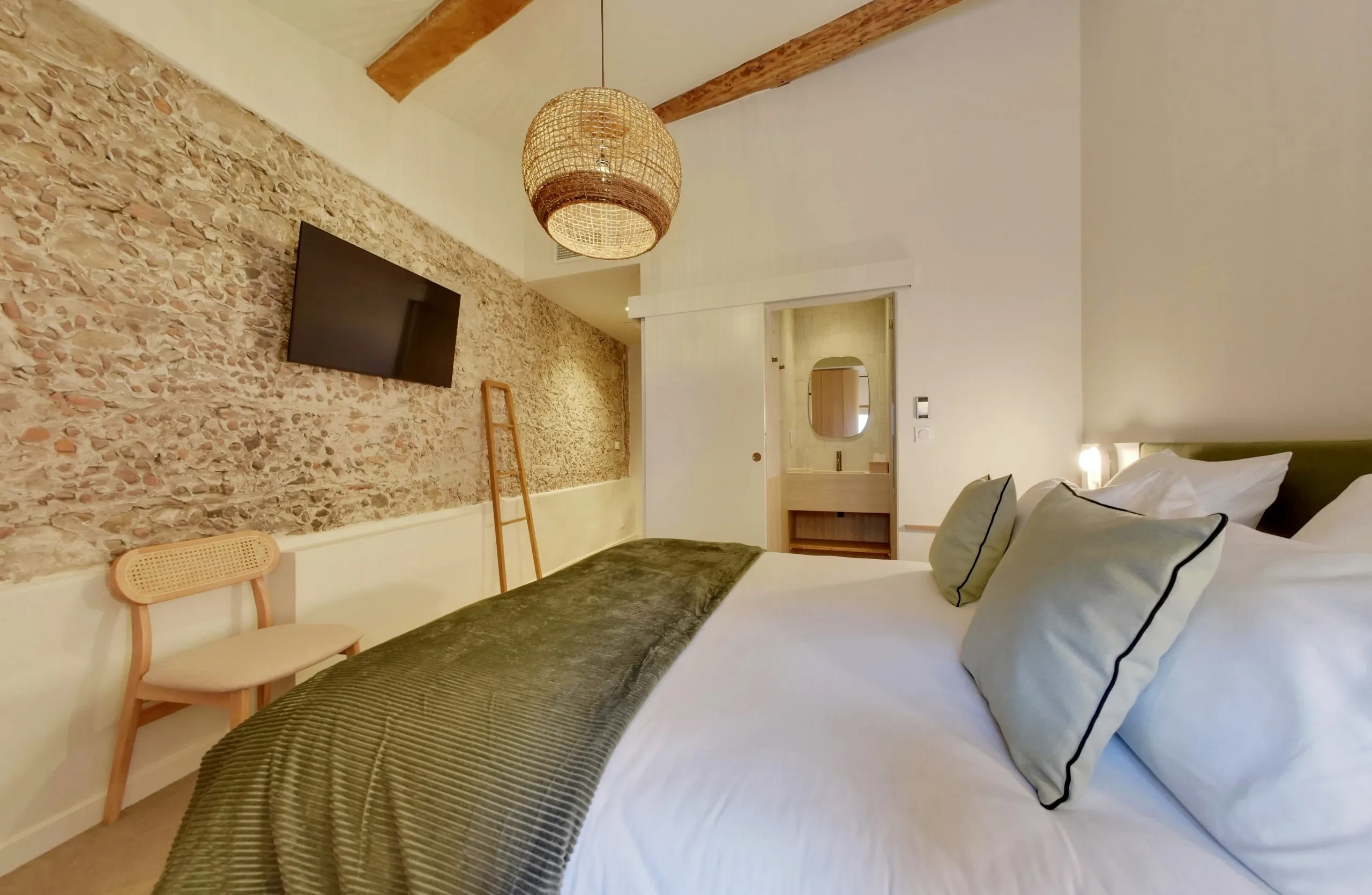 Chambre moderne avec lit et télévision murale.