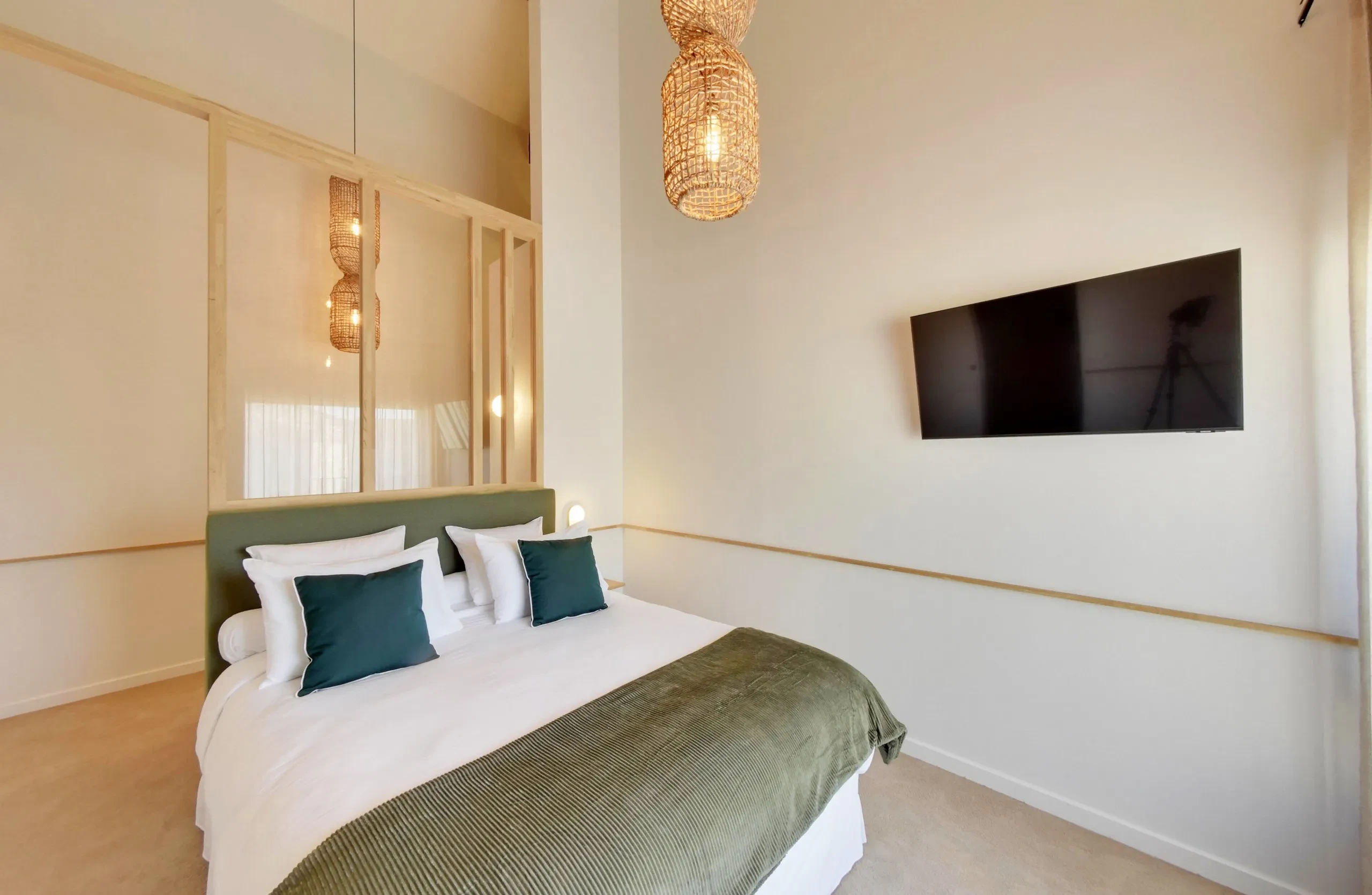 Chambre moderne avec lit et télévision murale.